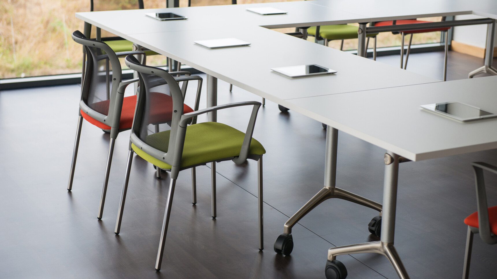 Five Elite Flip Top Rectangular Tables With White Finish And Silver Metal Leg Finish On Castors With With Seven Elite Chairs Three In Red Upholstery Three In Green Upholstery In Office Environment
