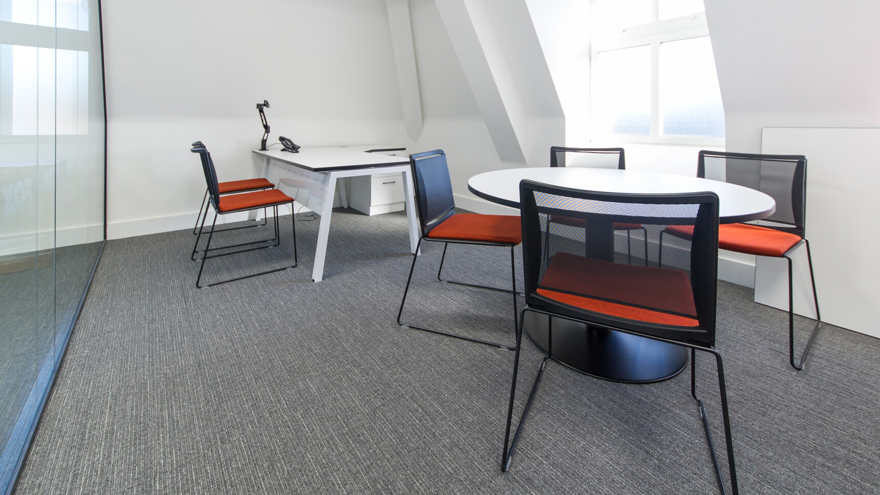 Elite Circular Meeting Table with Domed Base With White Table Top And Black Base With Six Elite Chairs With Red Upholstery And Black Backrest And Legs With Linnea Angular Workstation With White Finish And Black Edges