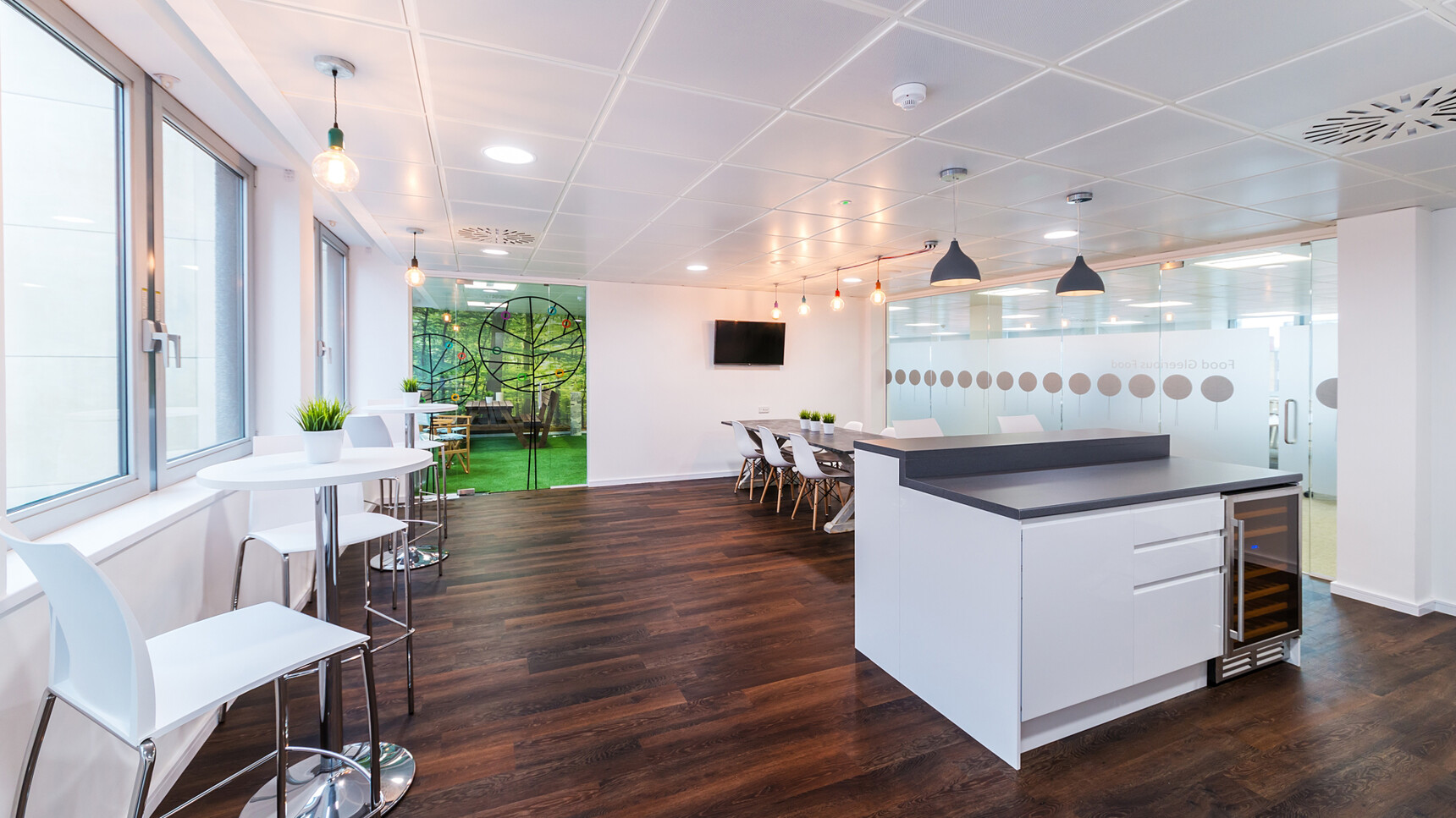 Two Elite Circular Bar Table with Chrome Trumpet Base With White Top And Chrome Base Finish With Six Ben Chairs With White Plastic Seat And Backrest And Wood Legs And Four White Elite Stools In Canteen