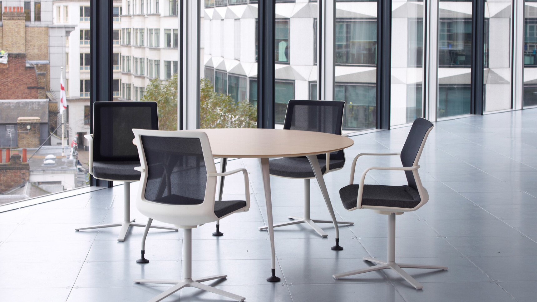 Orangebox Workday Conference Armchair With Black Upholstery And White Frame And Base At Meeting Table In Office Setting