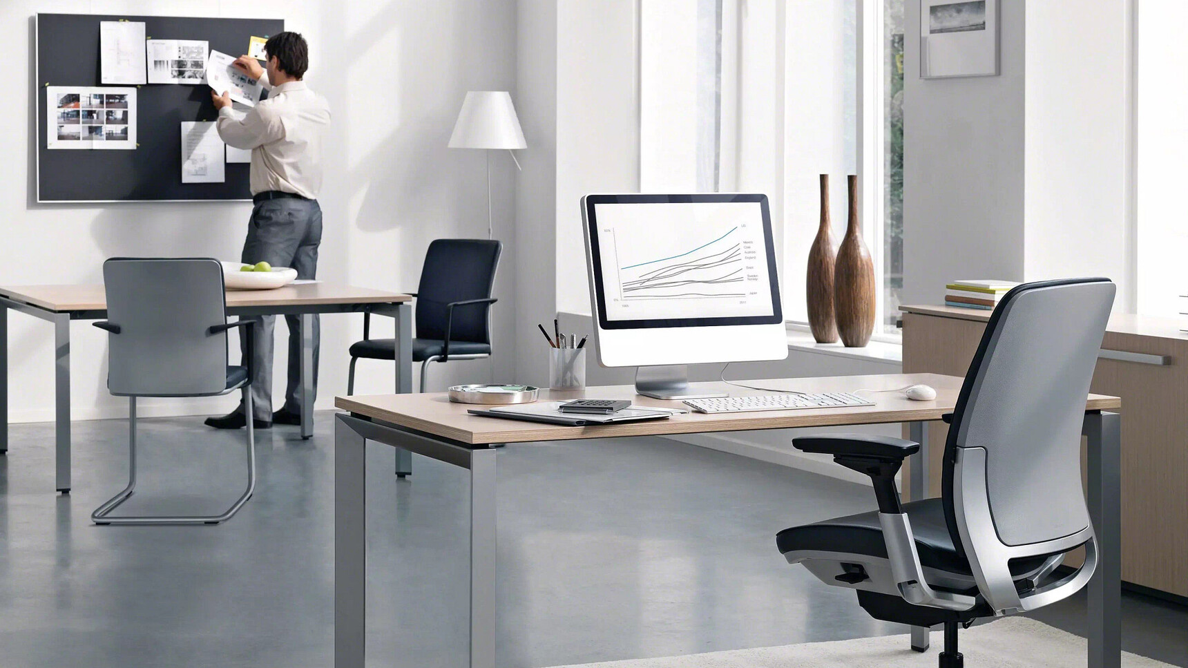 Steelcase Amia Platinum Office Task Chair At Table In Office With Two Chairs In The Background