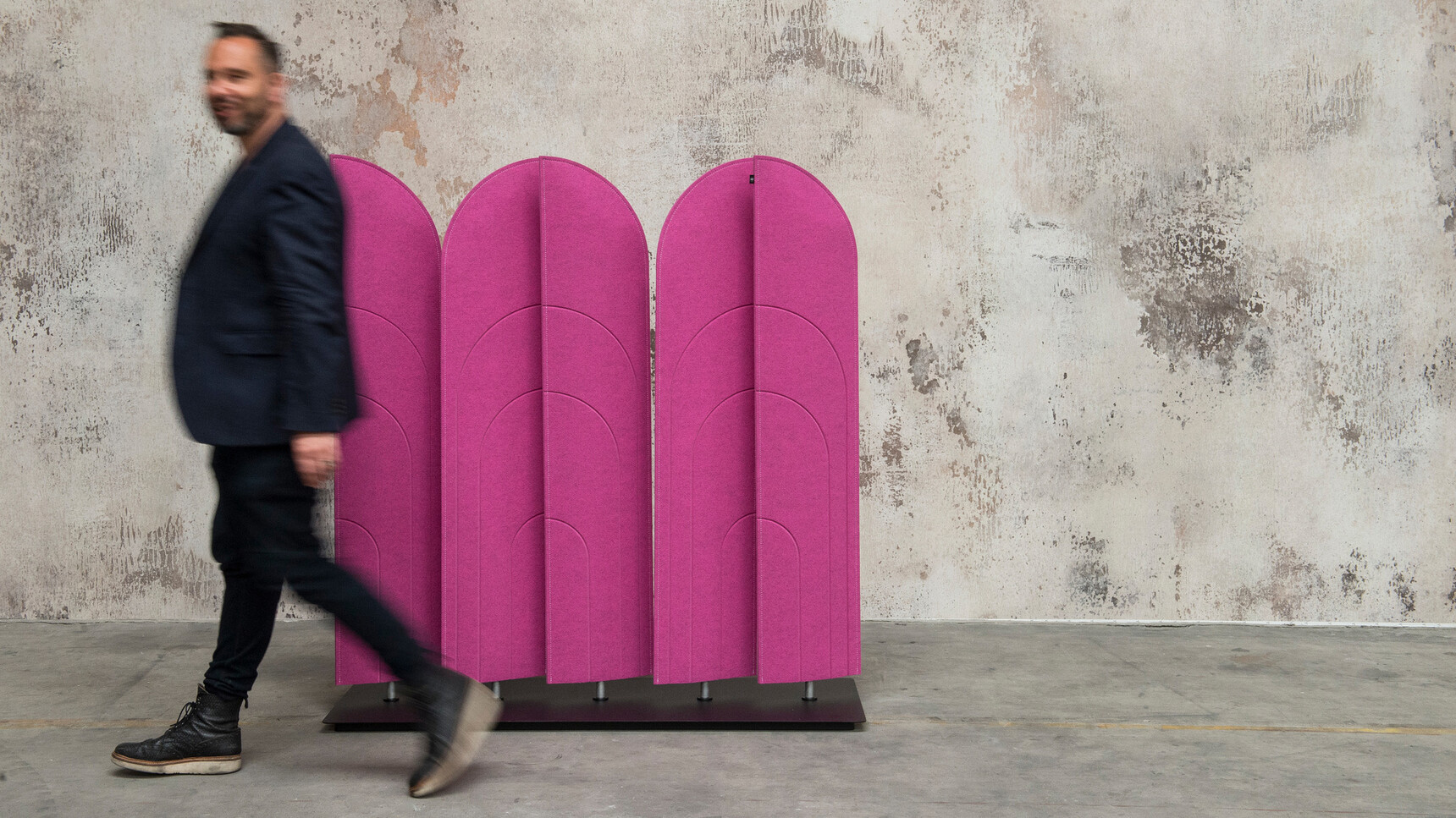 Buzzi Space BuzziBlinds Beach Acoustic Partition With Purple Upholstery Against Grey Wall With Person Walking Past