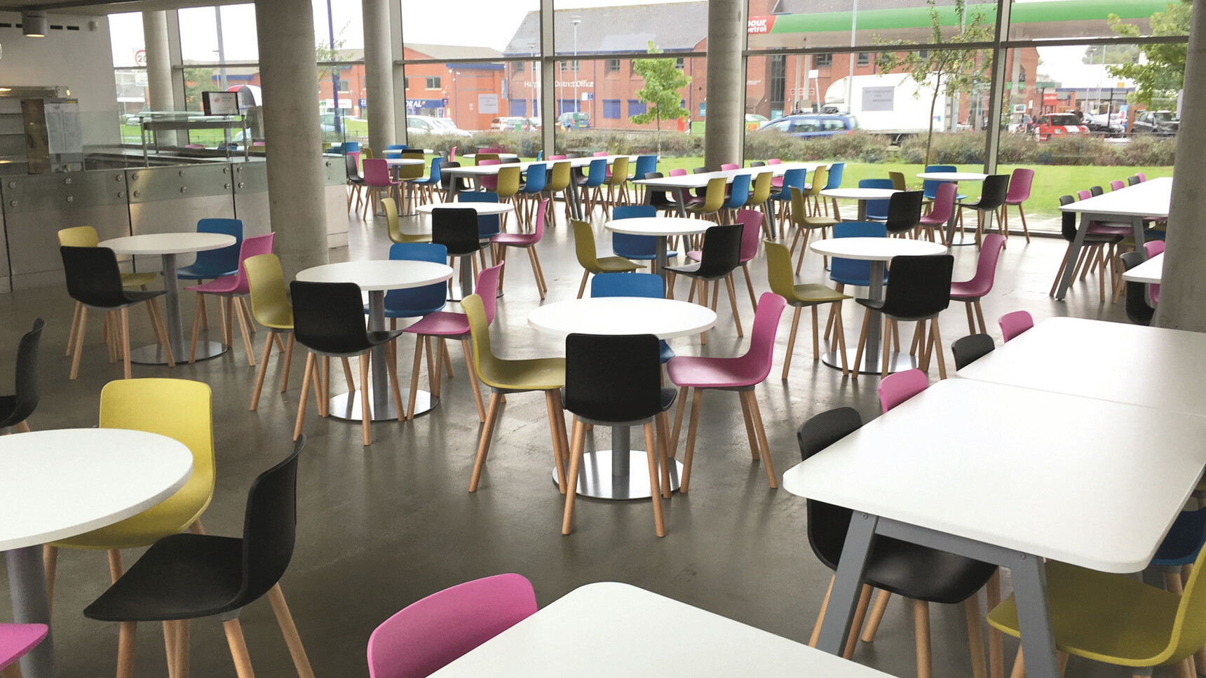 A Group Of Elite Ben Chairs In Black Blue Pink And Green At Circular Meeting Table with Round 600mm Base With Ten Linnea Tables In A Canteen