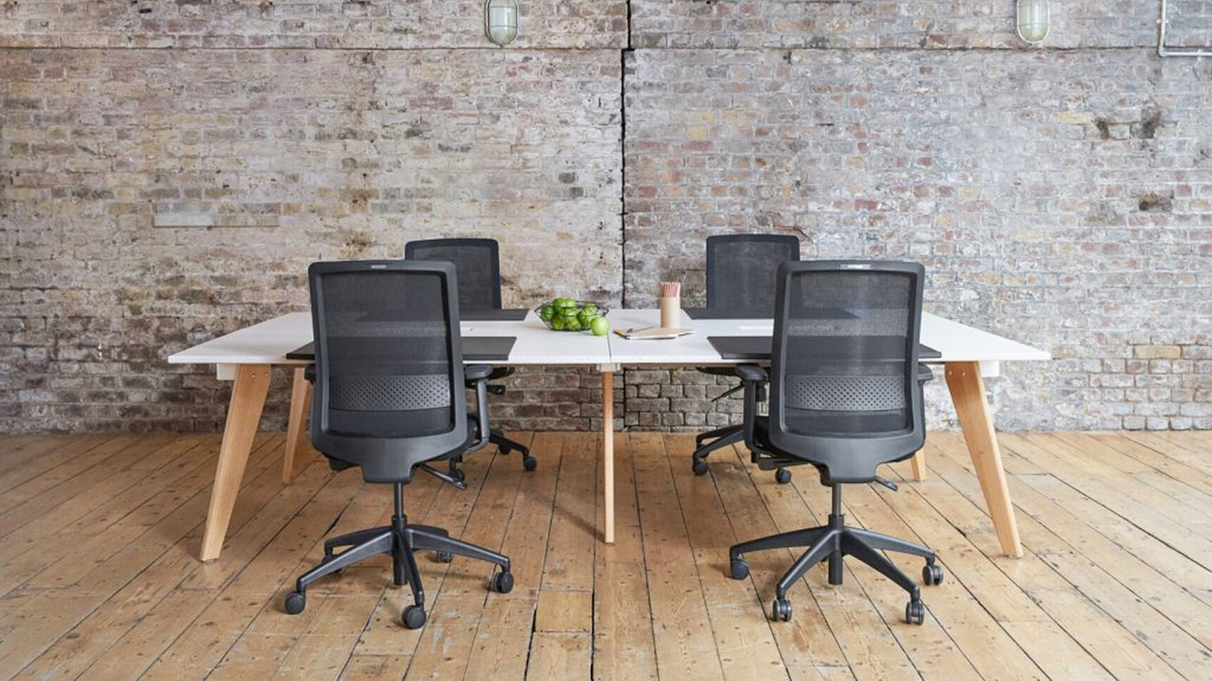 Workstories Hub Bench Desk White Top Oak Leg Four Chairs In Black In Office Setting