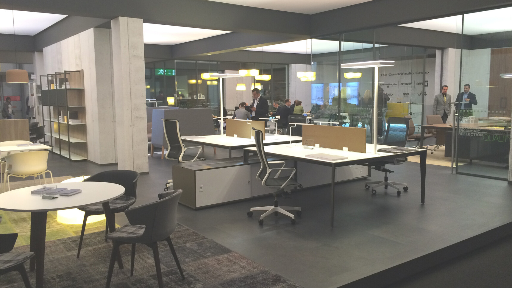 Two Quadrifoglio X5 Two Person Bench Desks 1238mm Depth With White Table Top Finish And Black Leg Finish And Two Brown Table Top Screens With Various Surrounding Office Furniture