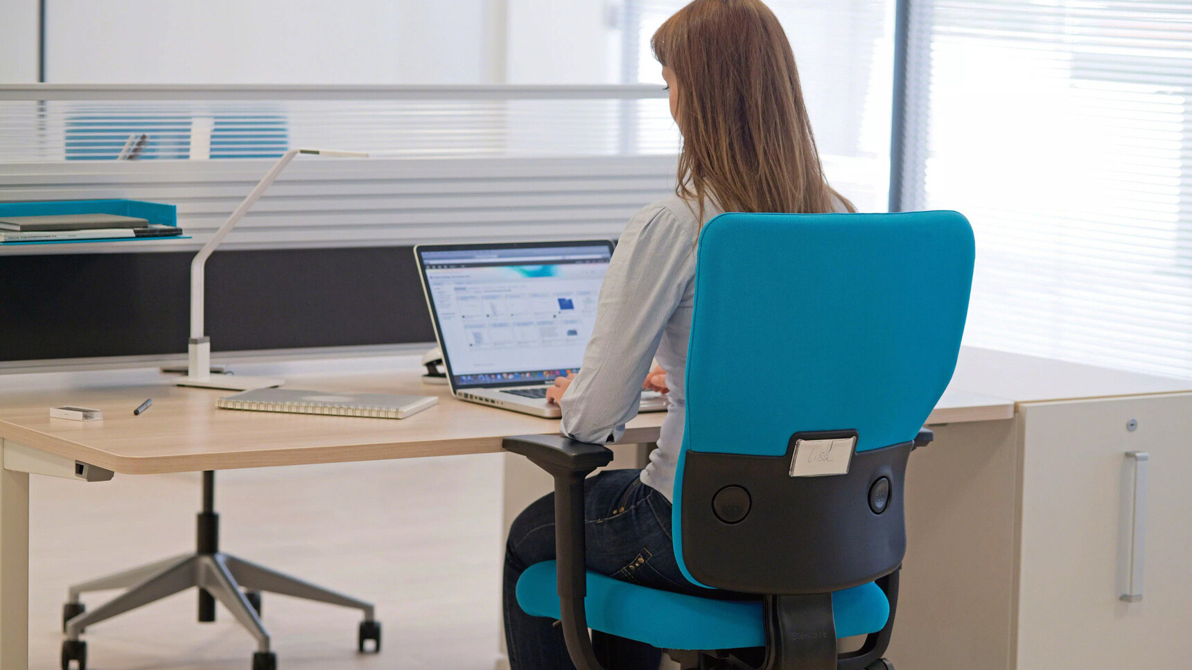 Steelcase Let's B High Back Office Chairs Blue Upholstery At Fixed Height Desk With Woman on Chair In Office Environment