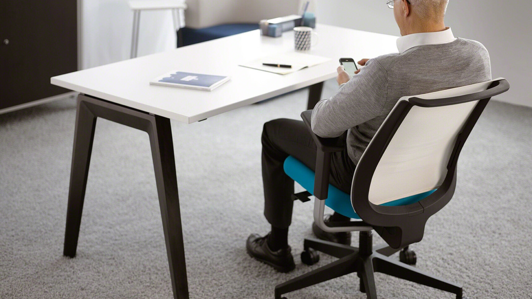 Steelcase B-Free Desk With White Table Top Finish And Black Leg Finish With Reply Air Mesh Back Office Chair With White Backrest And Blue Upholstery Detail Image