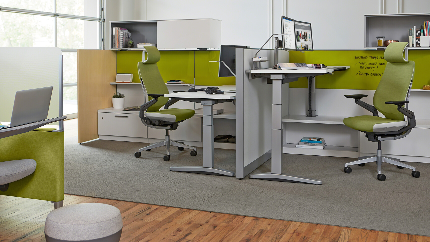 Two Steelcase Gesture Wrapped Back Office Chairs with Headrest And Green Upholstery At Height Adjustable Desks