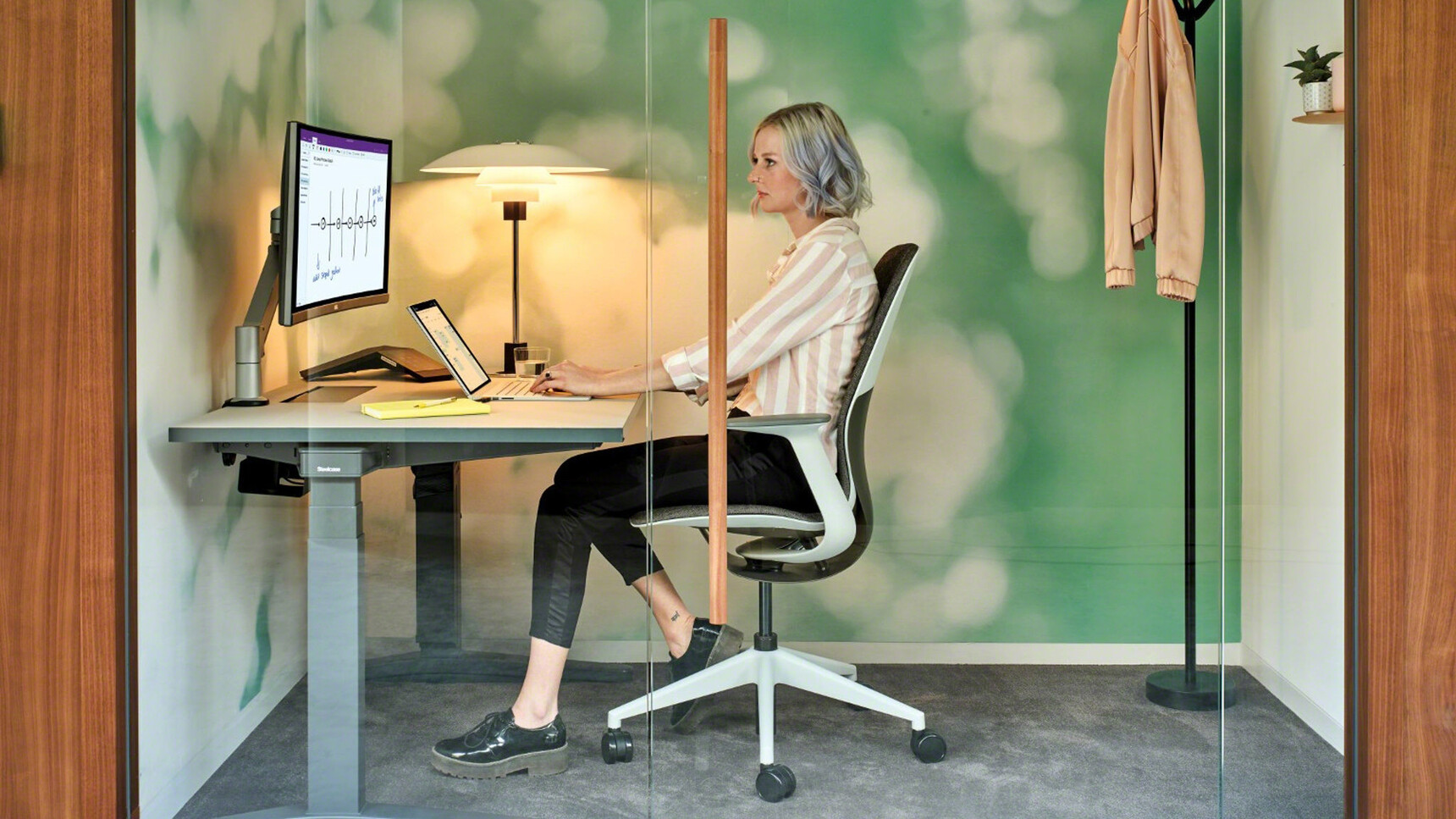 Steelcase Ology Fixed Height Desk With Wood Table Top Finish With Black Leg Finish With SilQ Upholstered Office Chair With Grey Upholstery And White Frame And Leg Base At Desk