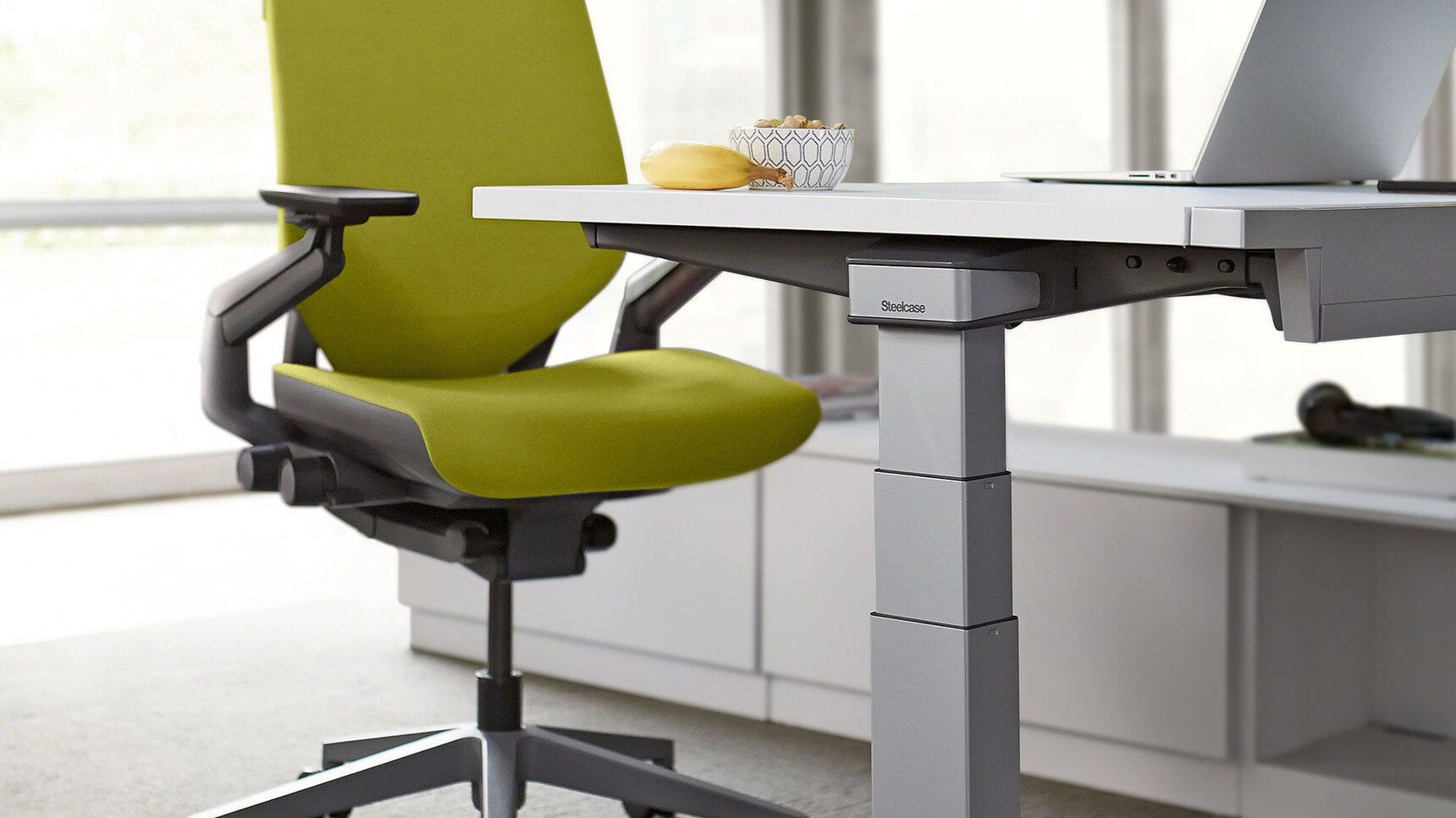 Steelcase Ology Height Adjustable Desks with Simple Touch With White Table Top Finish And Grey Metal Leg Finish With Gesture Wrapped Back Office Chair With Green Upholstery And Black Frame And Grey Base Detail Image