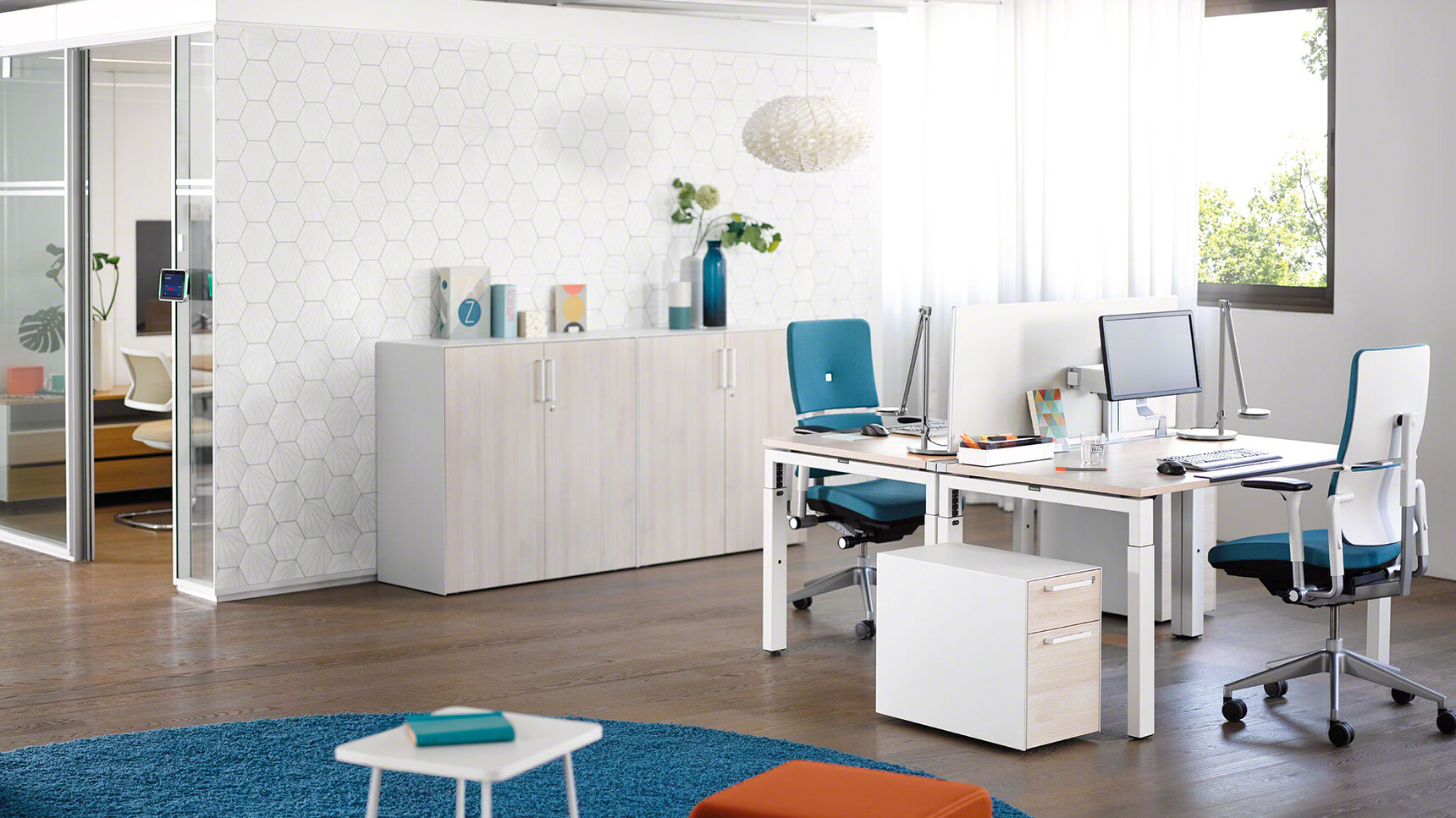 Two Steelcase Please Office Chairs With Blue Upholstery At Height Adjustable Desks With Wood Table Top Finish And Grey Metal Legs With Two Pedestals