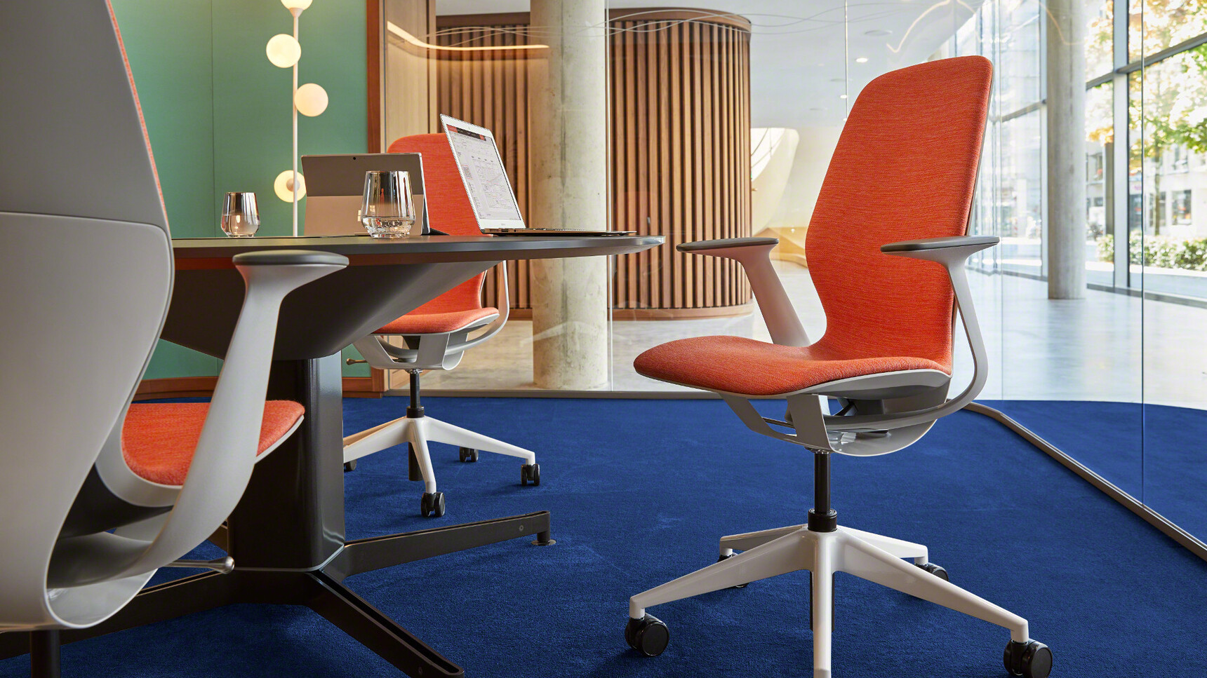 Three Steelcase SilQ Upholstered Office Chairs With Orange Upholstery With Grey Frame And White Base On Castors At Steelcase Desk Detail Image