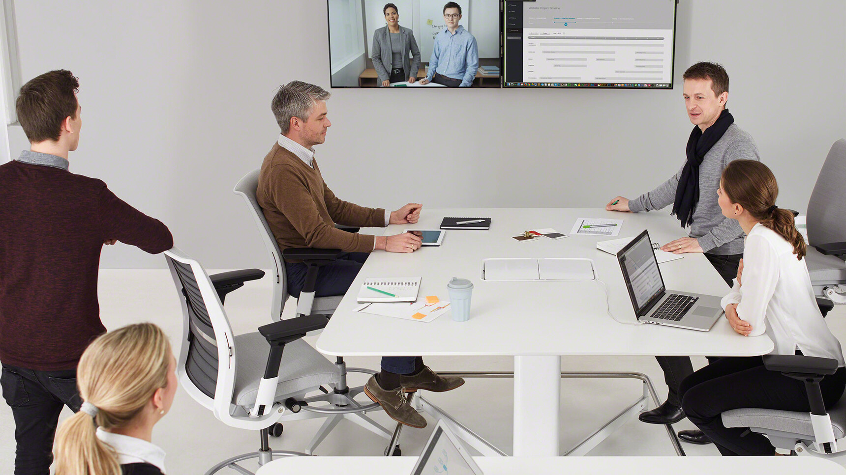 Four Steelcase Think Draughtsman Office Chairs Grey Upholstery Backrest White Black Armrest Grey Foot Ring Base At Table White Finish In Use