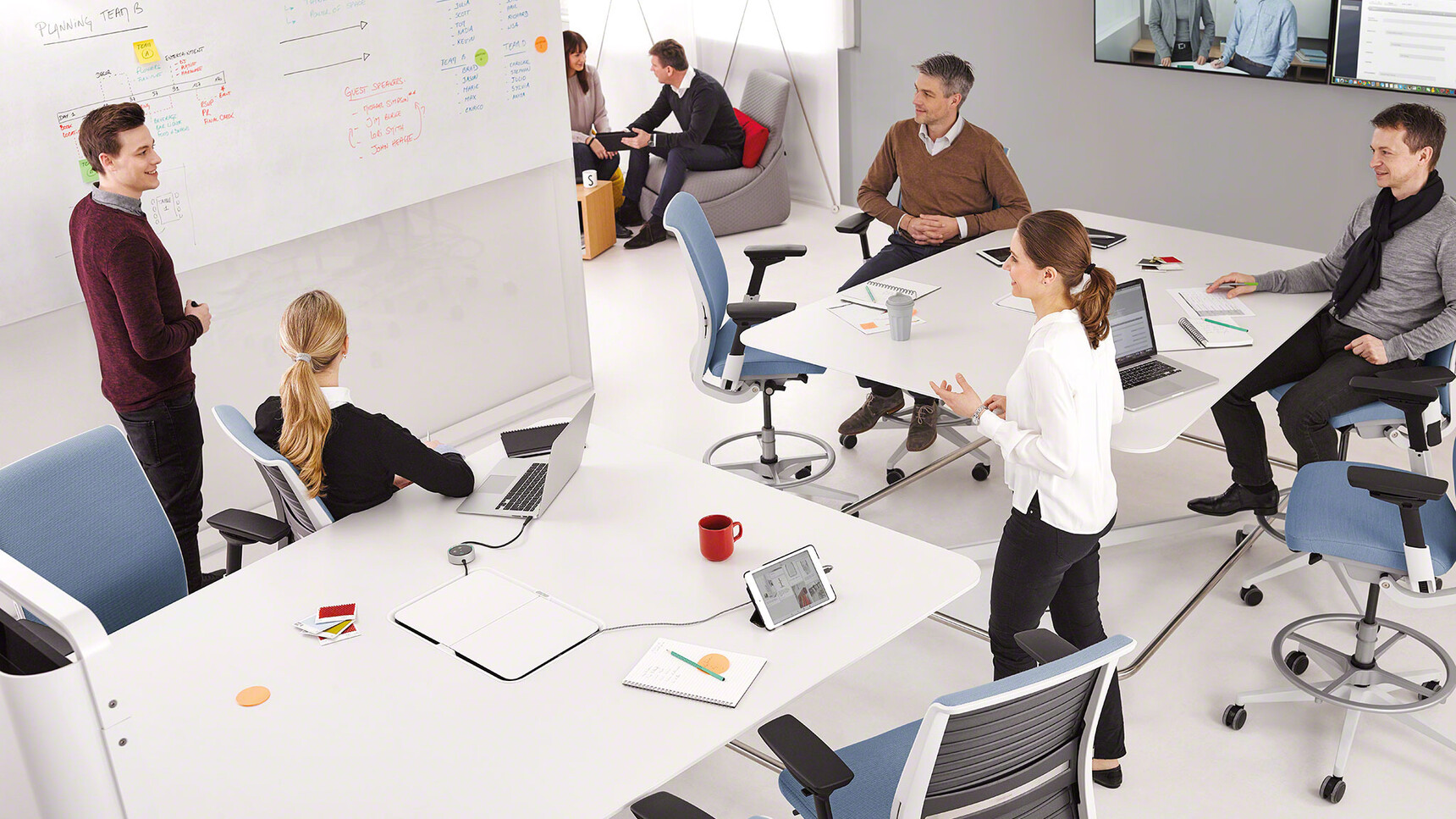 Eight Steelcase Think Draughtsman Office Chairs With Blue Upholstery With White Frame And White And Black Armrest With Grey Foot Ring And Base On Castors At Tables With White Finish On Conference Call