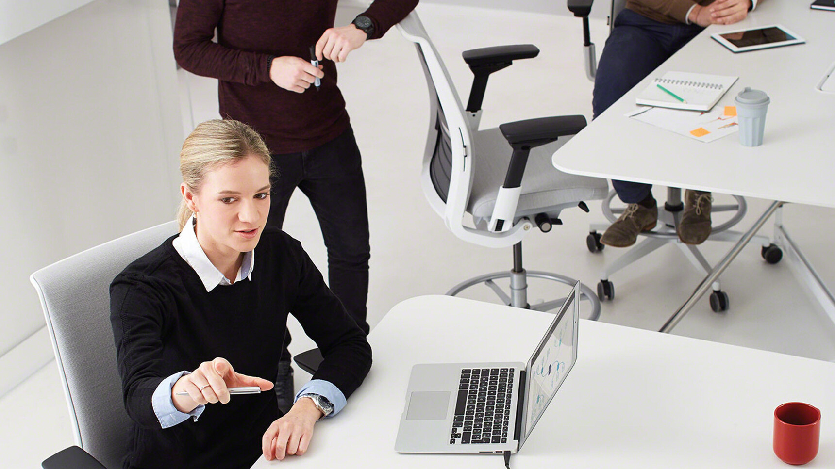 Three Steelcase Think Draughtsman Office Chairs Grey Upholstery Backrest White Black Armrest Grey Foot Ring Base At Tables White Finish In Use