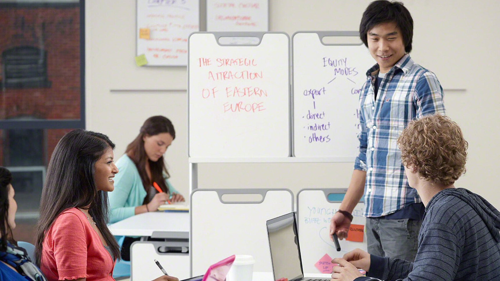 Four Steelcase Verb Chevron for Two Desks With White Table Top Finish Three With Optional White Board Easels In Use By Five People In Educational Environment