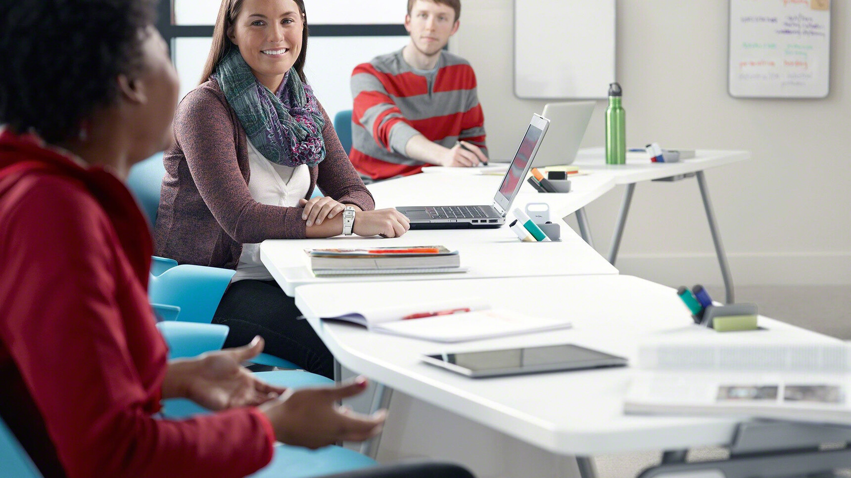 Four Steelcase Verb Rectangular Desks With White Table Top Finish And Grey Leg Finish With Node Chairs In Blue Upholstery In Use By Three People Detail Image