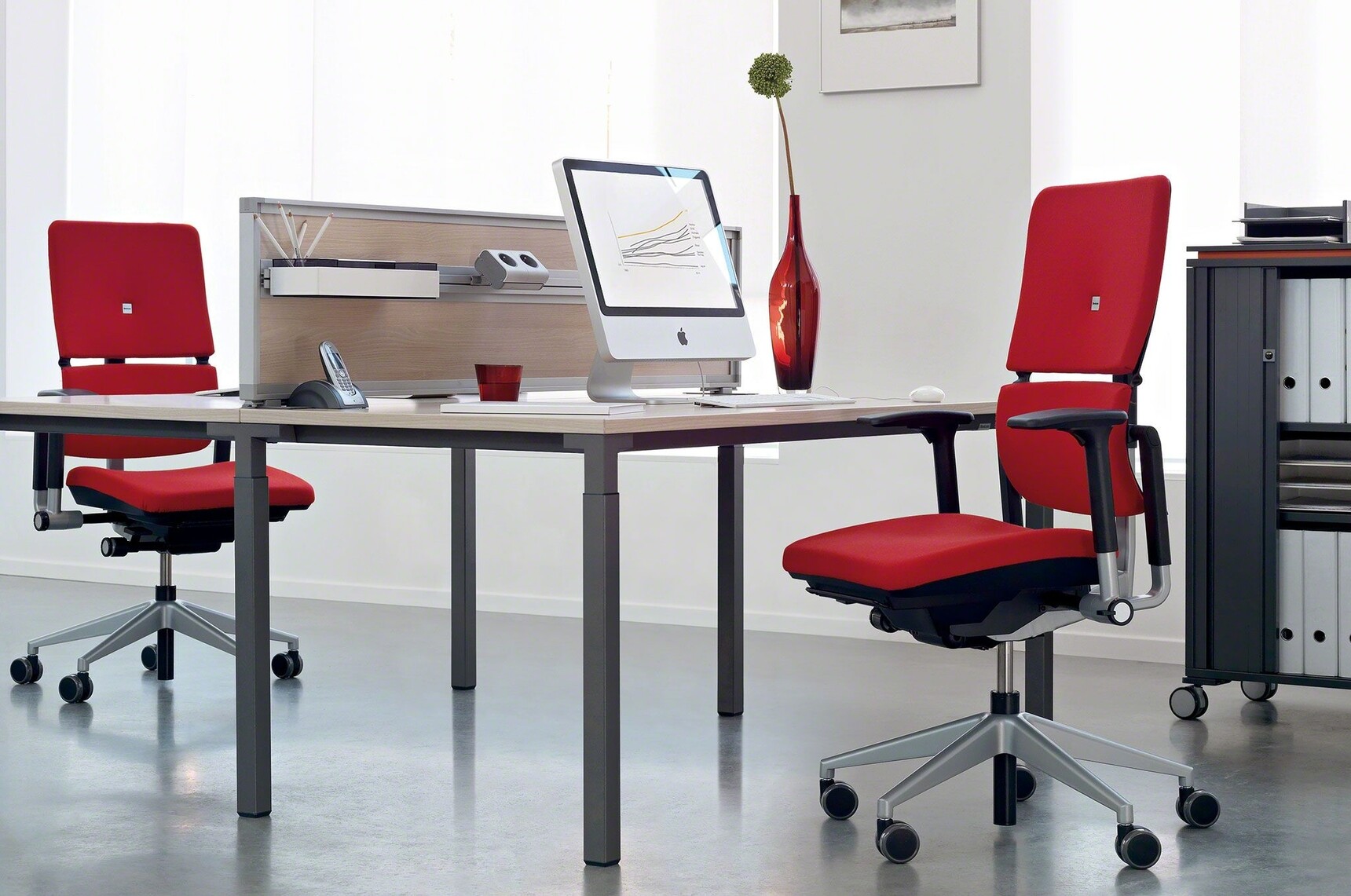Two Steelcase Please Office Chairs With Red Upholstery And Light Grey Fame Base With Castors And Fixed Black Arms At Desk In Office Environment