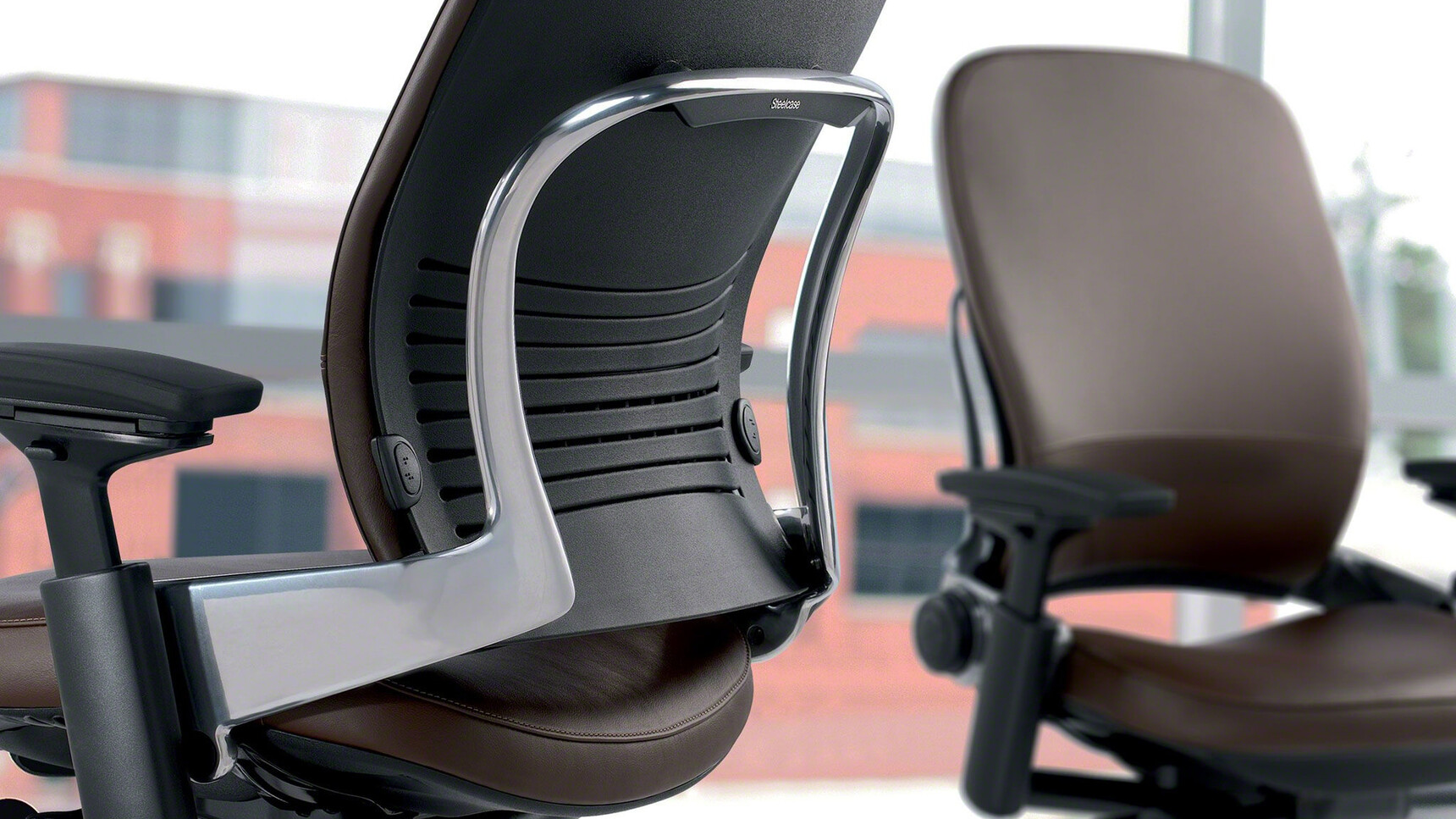 Two Steelcase Leap Leather Office Chairs With Brown Leather Seat And 4-D Arm Options Showing One Front Angle View And One Back Angle View Close Up