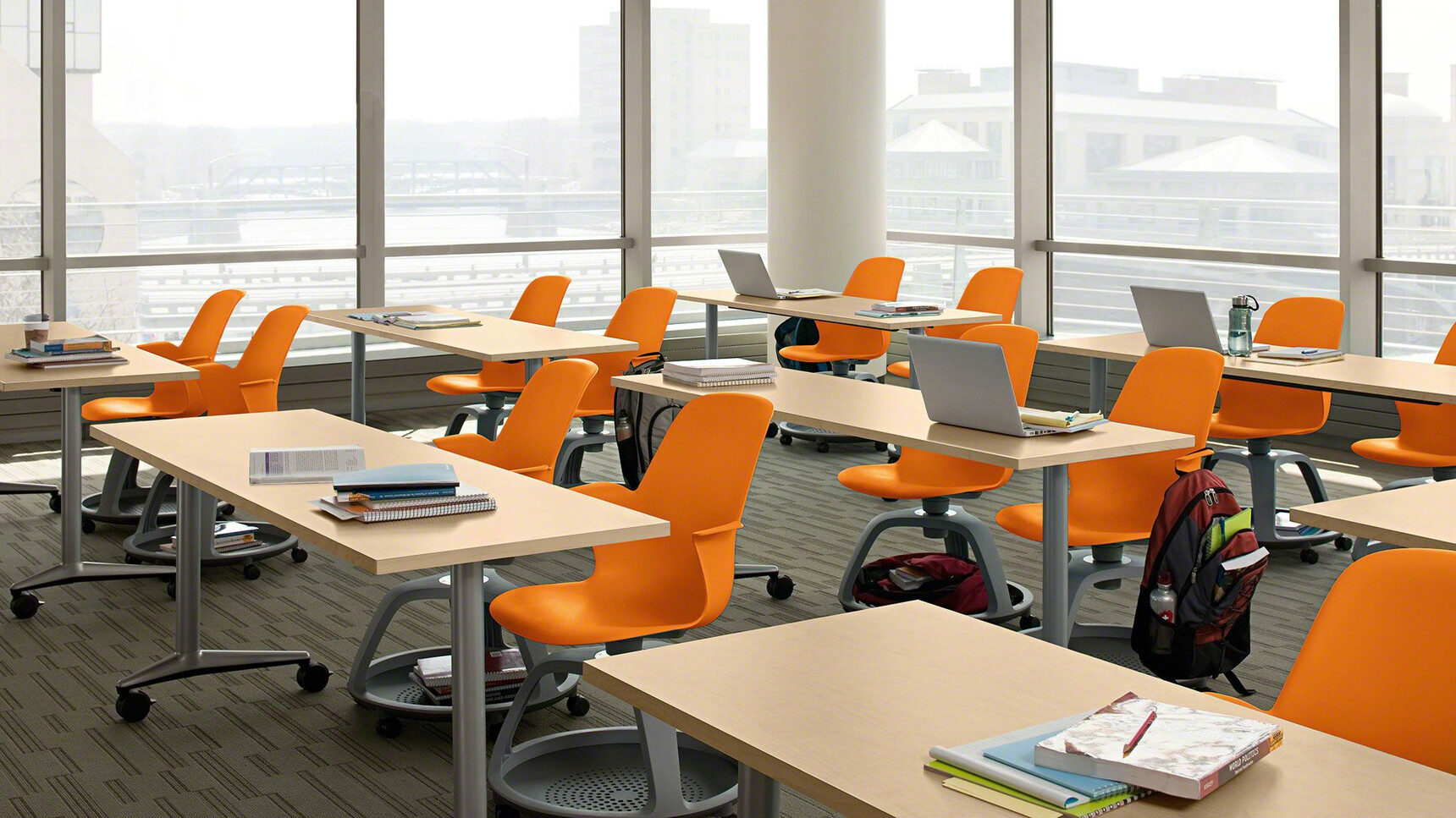 Thirteen Steelcase Node Tripod Base Chairs without Table With Plastic Back And Seat In Orange With Near Black Frame And Castors At Desks In Educational Environment
