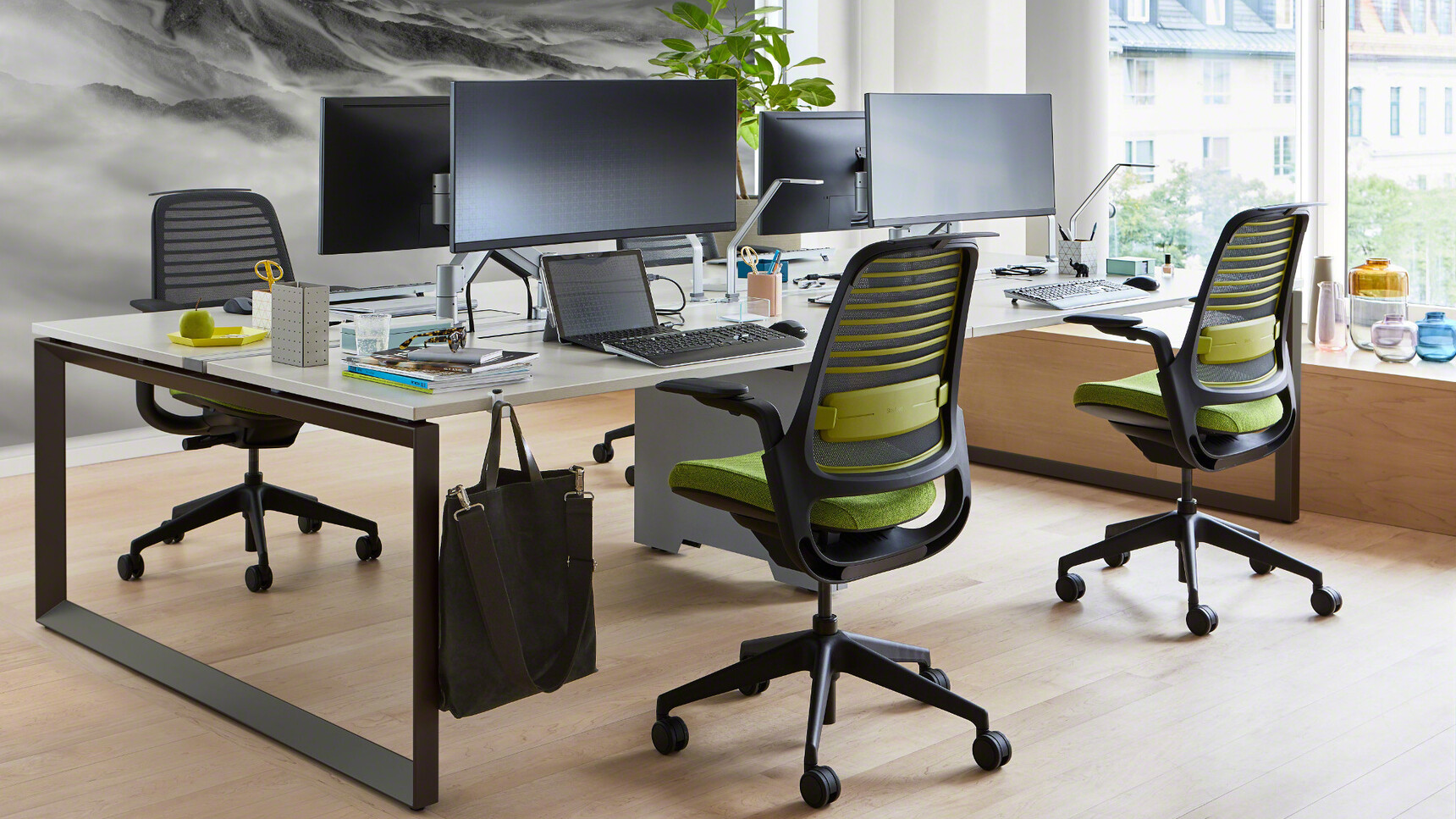Steelcase Frameone Bench Desk With White Table Top Finish And Black Loop Leg Finish With Four Steelcase Series One Chairs In Green Upholstery And Black Frame And Base On Castors At Desk