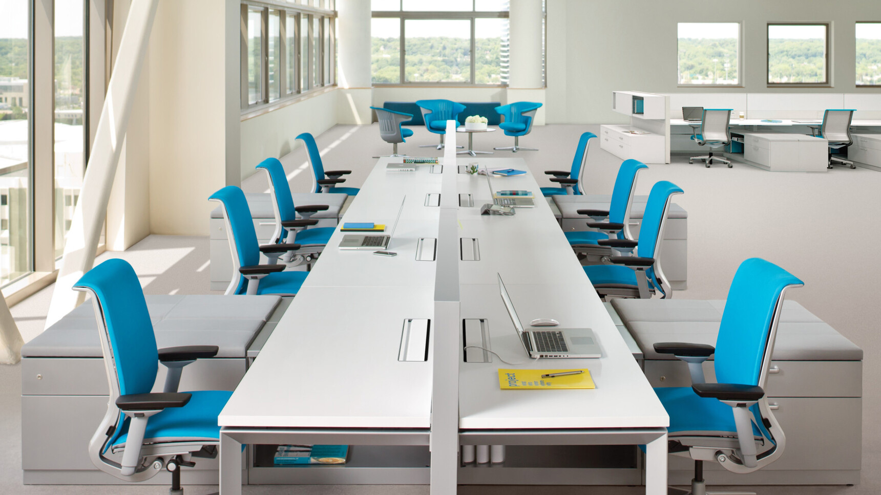 Steelcase Frameone Loop Leg Bench Desk With White Table Top Finish And Grey Metal Leg Finish With Eight Think Upholstered Office Chairs In Blue Upholstery And Grey Frame At Desk