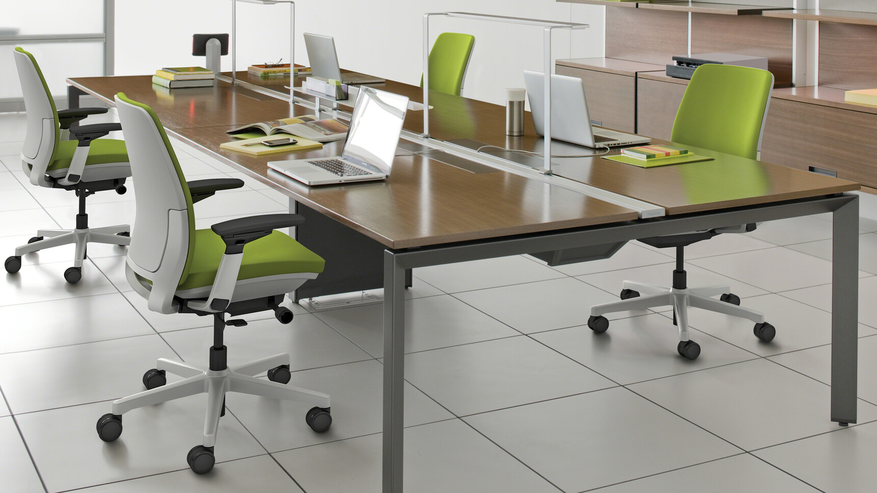 Steelcase Frameone Goalpost Leg Bench Desk With Dark Wood Table Top Finish With Black Leg Finish And Four Steelcase Office Chairs In Green Upholstery At Desk