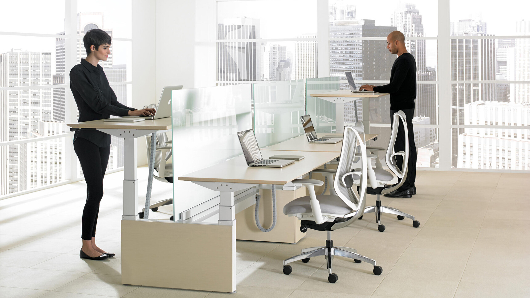 Two Okamura Sabrina Office Chairs Light Grey Upholstery White Frame Additional Lumbar Support White Grey 4-D Arms Polished Base Two People Using Height Adjustable Desks