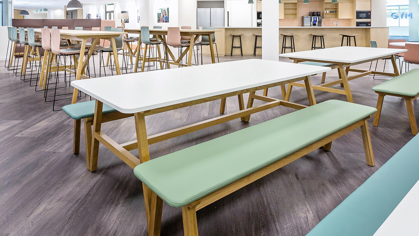 Four Boss Design Agent Benches Two With Light Green Upholstery Two With Light Blue Upholstery At Agent Four Leg Tables With White Table Top Finishes