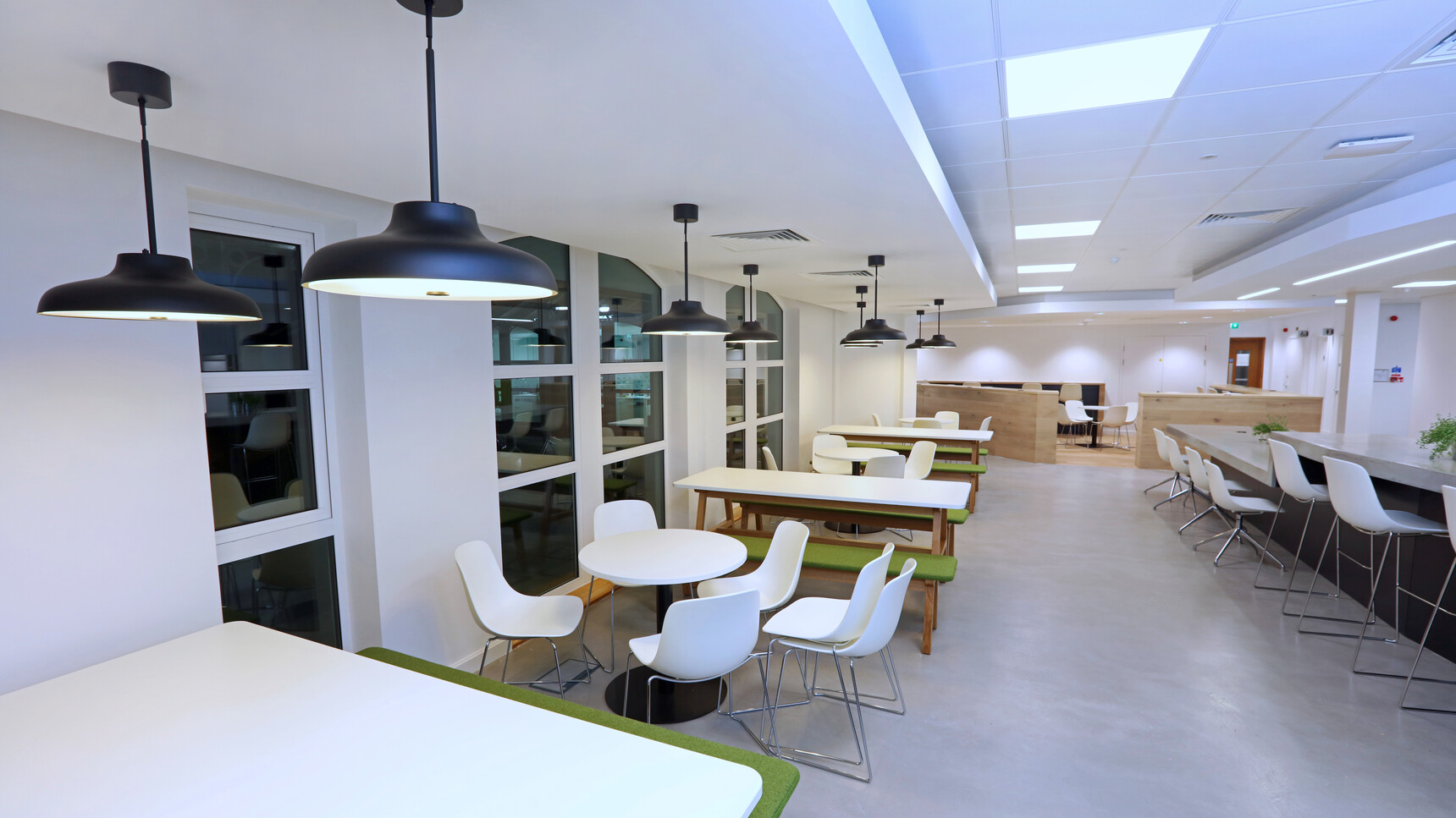 Five Boss Design Agent Benches In Green Upholstery And Wood Timber Four Leg Base At Three Agent Four Leg Tables With White Table Top Finish And Wood Base Finish In Canteen Environment
