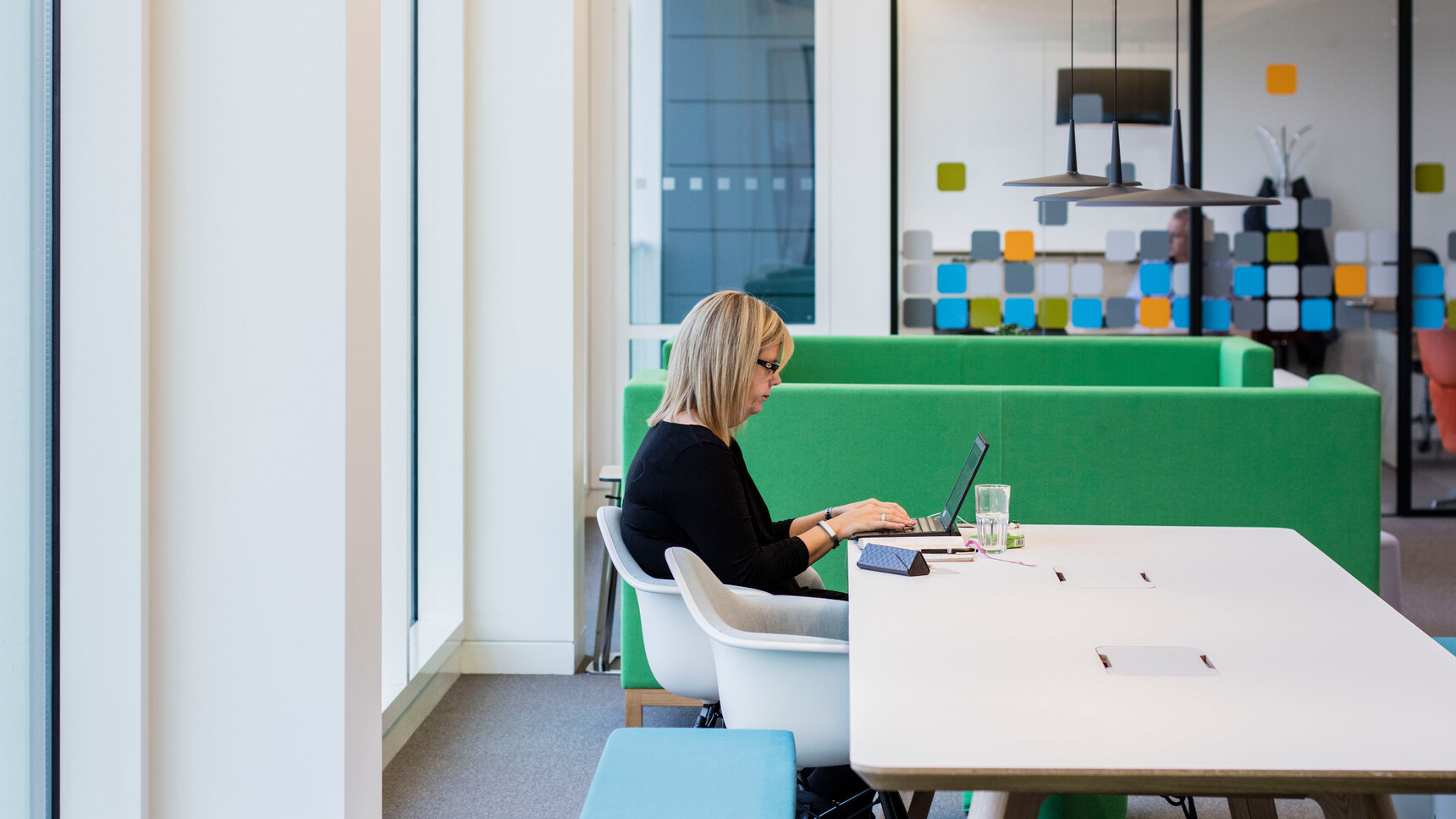 Two Boss Design Arthur Large Sofas In Green Upholstery Facing Each Other With A Person On A Chair At Desk Using Her Computer