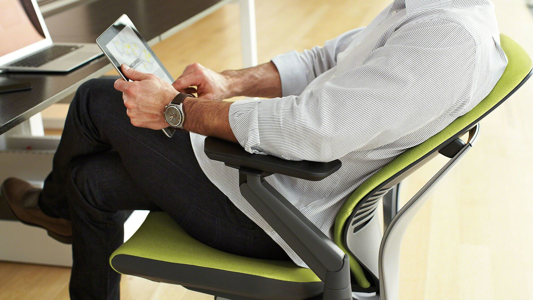 Steelcase Gesture Shell Back Office Chair With Green Upholstery And Black Grey Frame And Black Arms In Use By A Person On A Tablet Detail Image