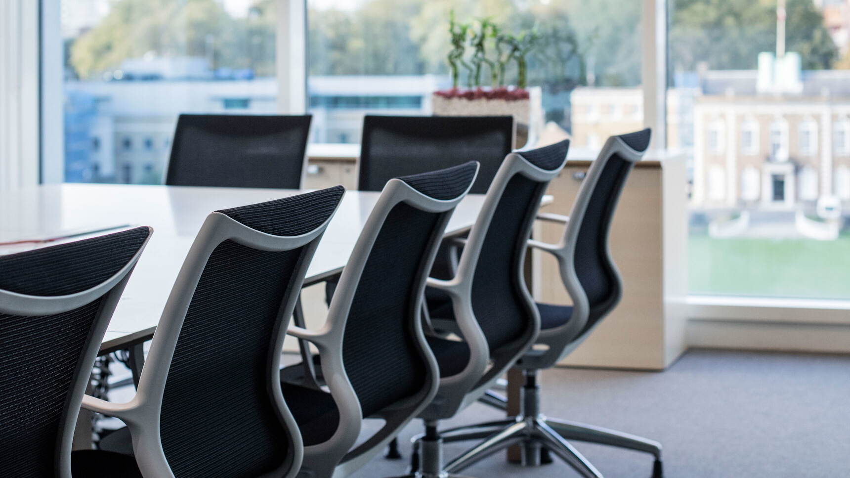Seven Boss Design Kara Office Chairs with Arms In Black Upholstery And White Armrests And Polished Aluminium Base On Castors At Desk Detail Image