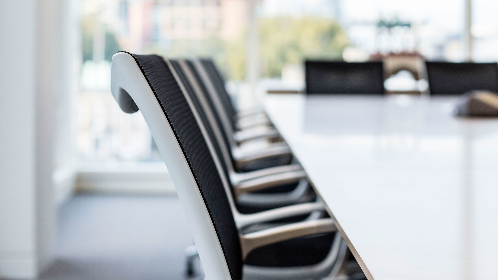 Several Boss Design Kara Office Chairs with Arms In Black Upholstery With White Frame And White Armrests At Table Detail Image