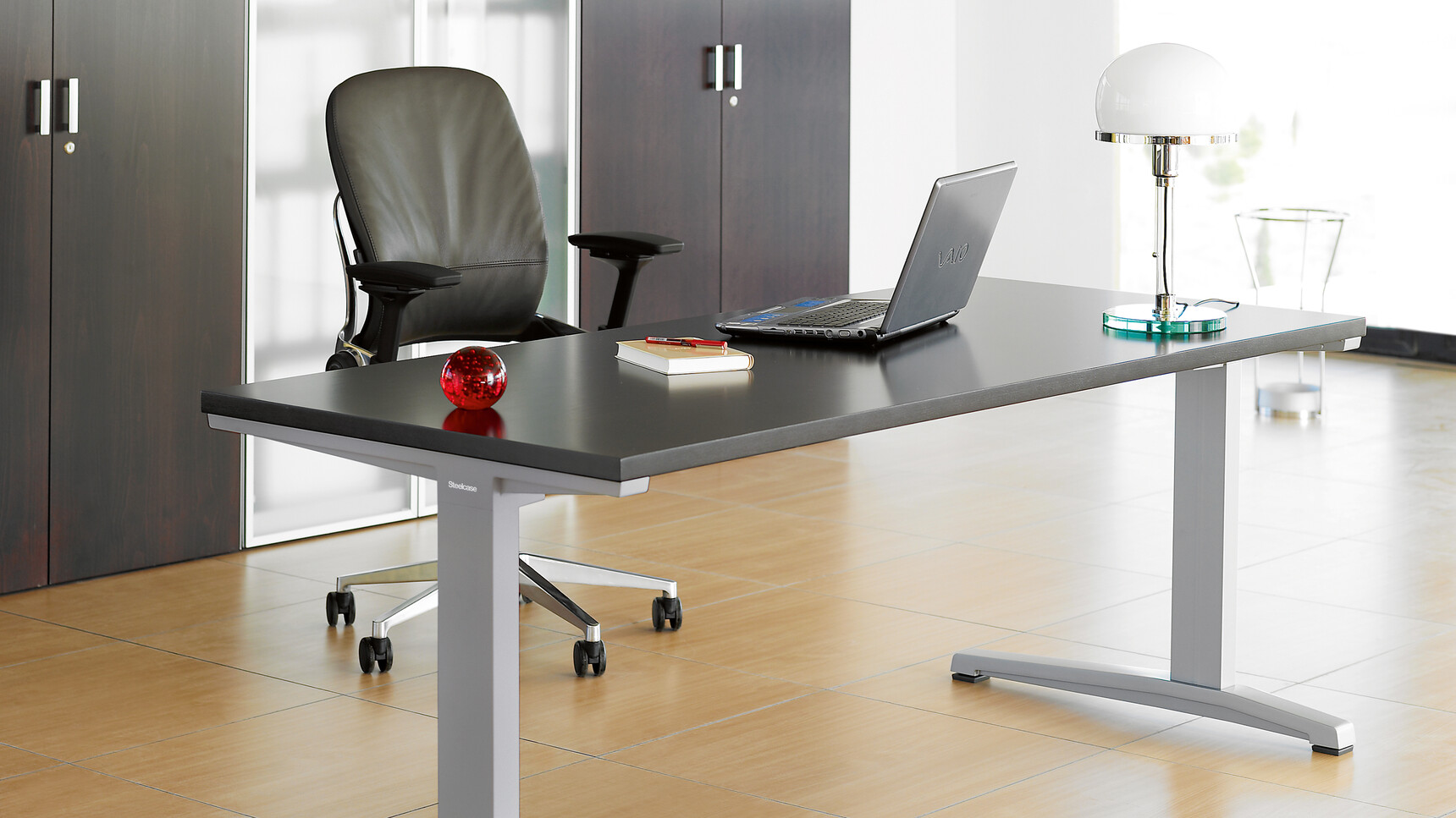 Steelcase Leap Leather Office Chairs With Black Leather Seat And 4-D Arm Options And Polished Aluminium Base At Ology Fixed Height Desk With Platinum Metallic Leg Finish And Black Table Top In Office Environment