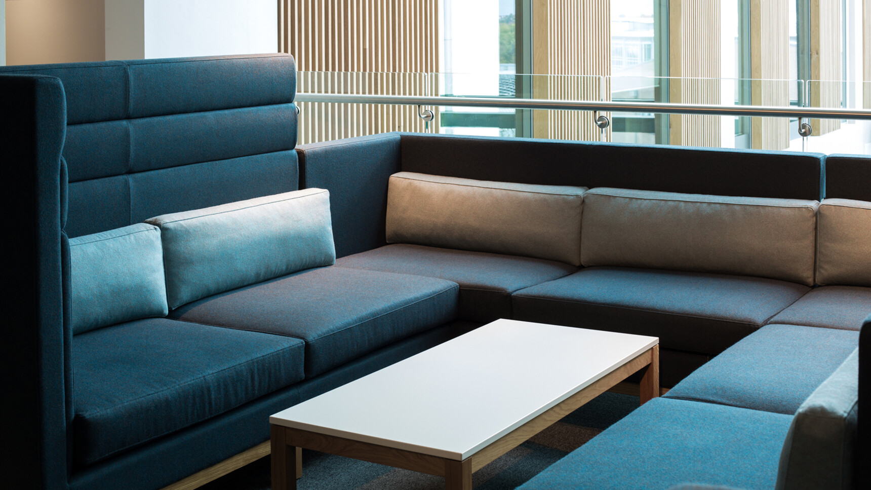 Boss Design Arthur Cityscape With Dark Grey Blue Upholstery With Wood Leg Finish With High And Low Seating And White Cushions At Coffee Table