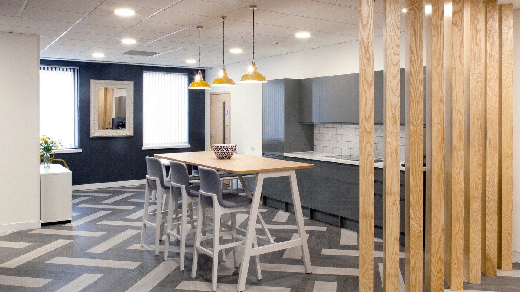 Elite Harmony Poseur Height Table With Support Frame With Wood Finish And Silver Leg Finish With Three Bill Upholstered Stools In Blue Upholstery And Metal Silver Leg Finish In Kitchen Environment