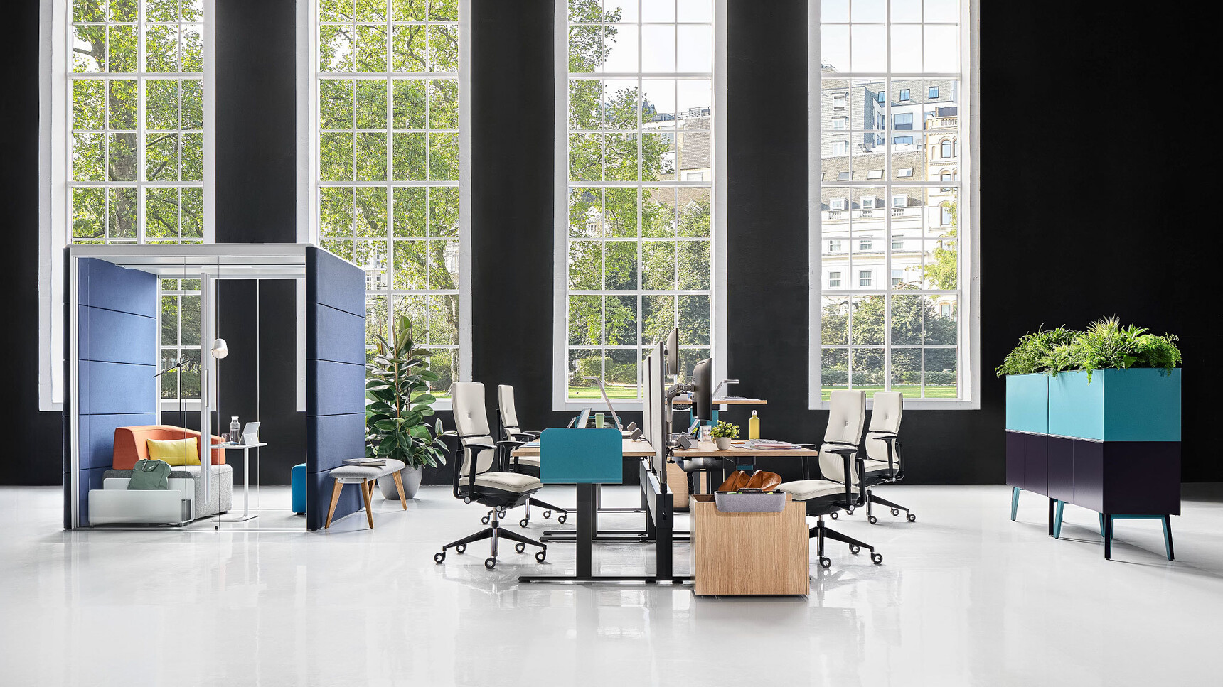 Steelcase Migration SE Height Adjustable Bench Desks With Wood Table Top Finish And Black Leg Finish Blue privacy Screens Four Steelcase Chairs In Office Environment