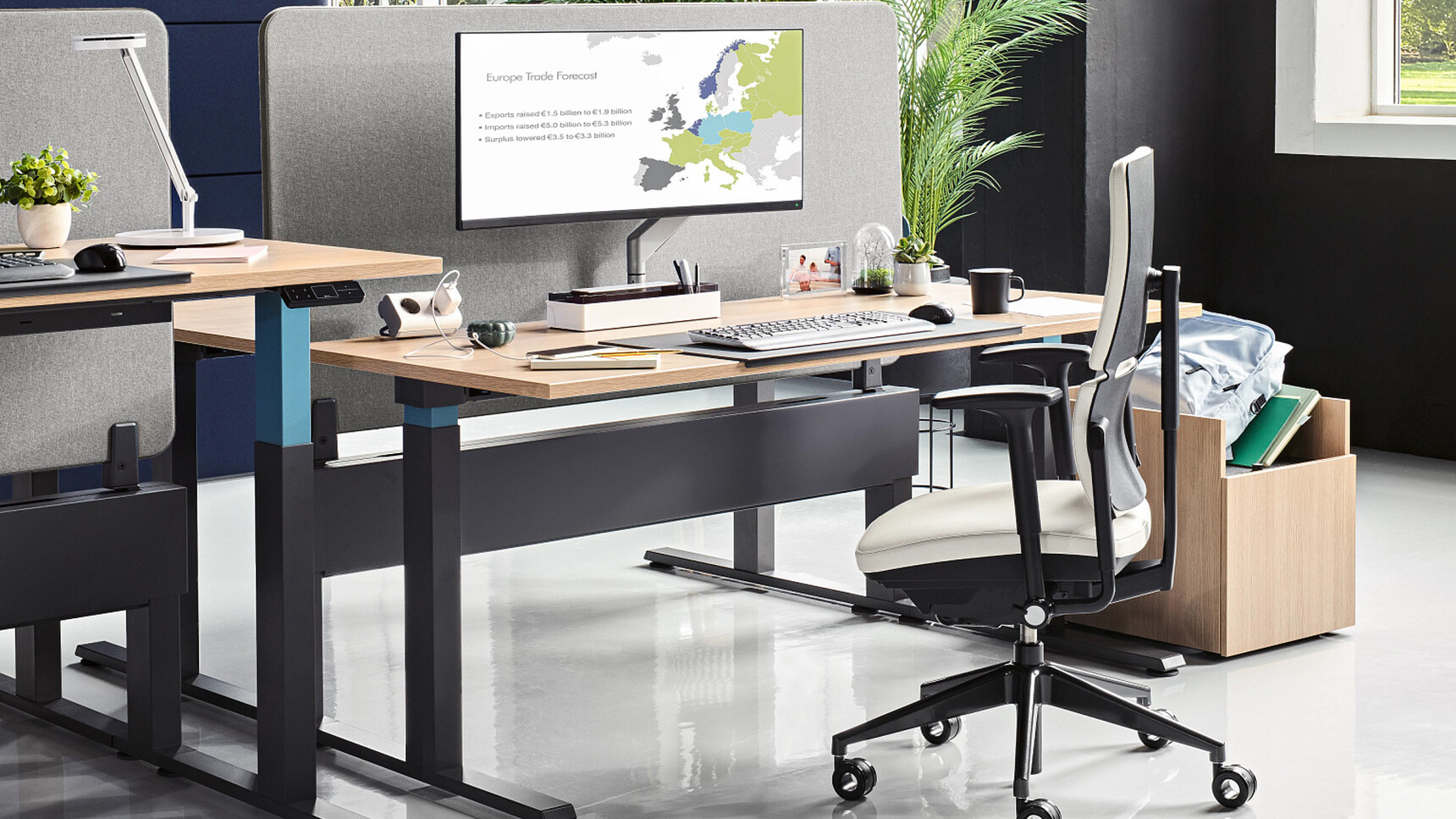 Steelcase Migration SE Height Adjustable Bench Desks With Wood Table Top Finish And Black Leg Finish And Steelcase Chair In Office Environment Image Two