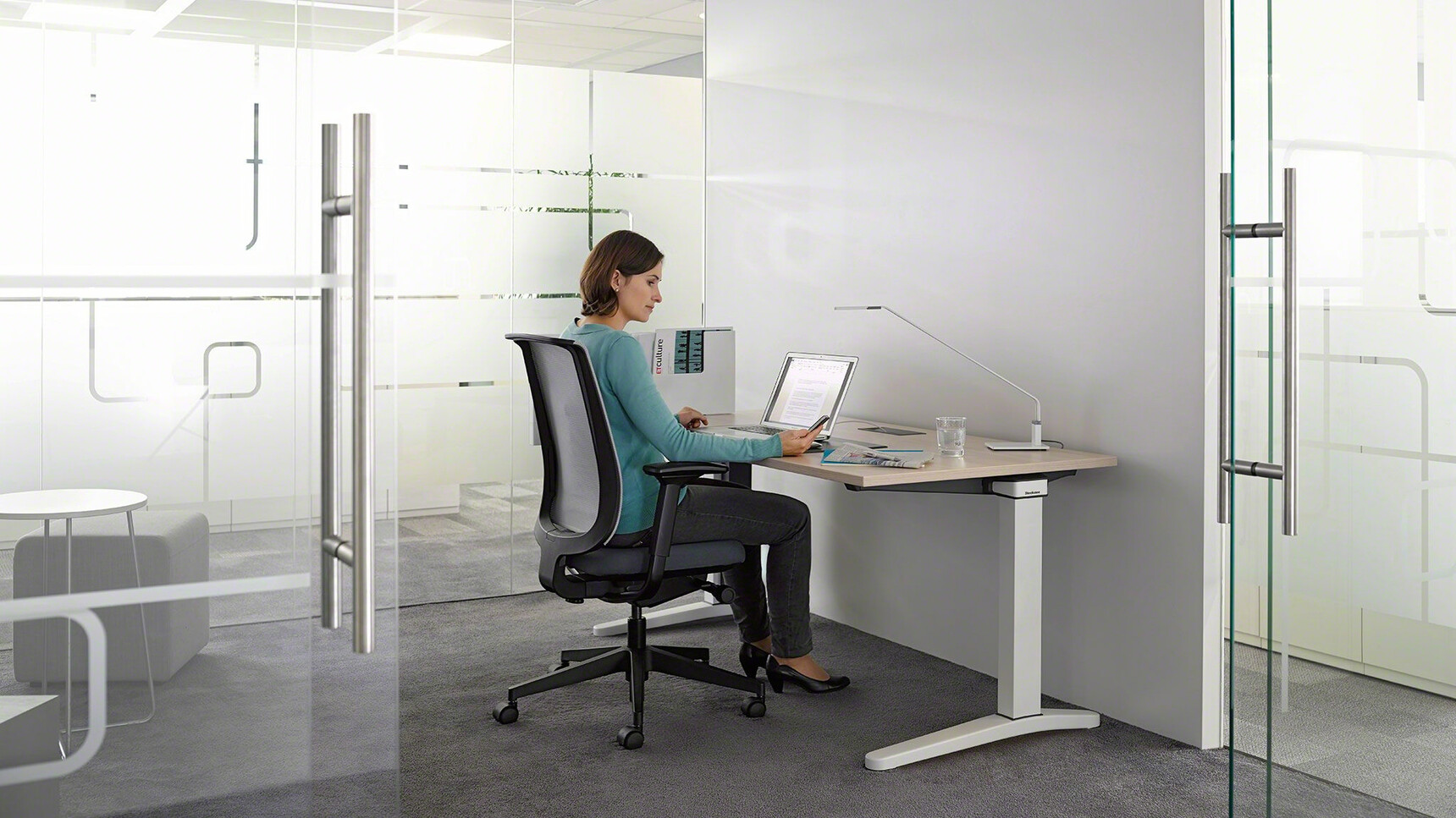 Steelcase Ology Fixed Height Desk With Platinum Metallic Legs And Wood Table Top Finish With Steelcase Office Chair With Blue Upholstery In Office Environment