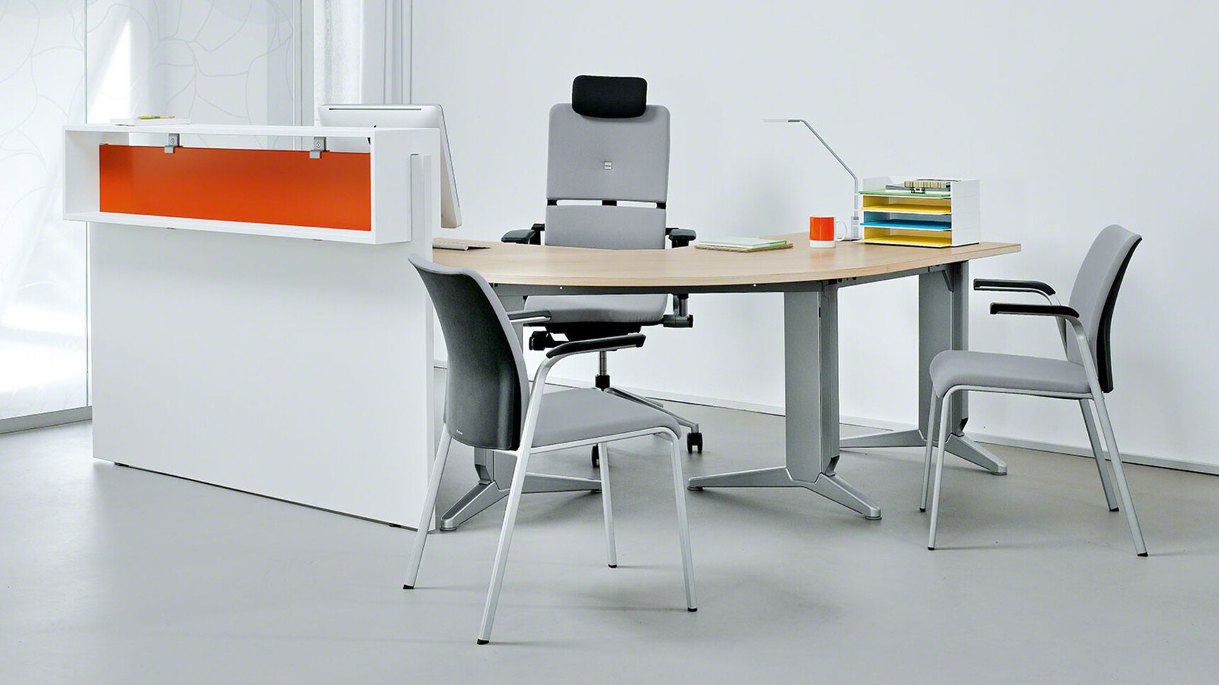 Two Steelcase Eastside Four Leg Base Meeting Chairs With Grey Upholstered Backrest Black Fixed Arms And Grey Seats And Grey Base At Desk With Please Executive Office Chair In Office Environment